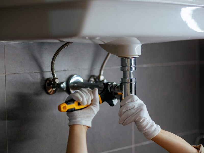 A,Plumber,Tightens,A,Chrome,Drain,Pipe,Under,A,White